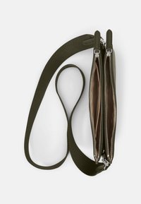 Bolso de color verde oliva con dos compartimentos, textura suave, cremalleras plateadas y una correa plana, diseñado para llevarlo cruzado.