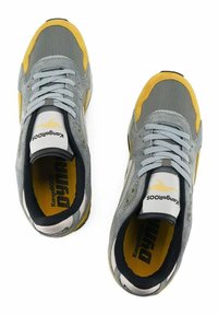 Graue und gelbe Sportschuhe mit einem Obermaterial aus Mesh, Wildlederakzenten und einem gepolsterten Schaft. Sie verfügen über ein Logo an der Zunge und eine strukturierte Sohle.