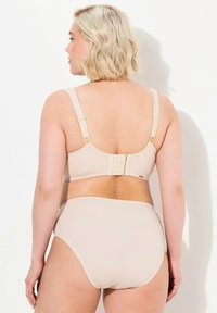 Beige podprsenka s nastavitelnými ramínky a zapínáním na tři háčky vzadu, v kombinaci s bikiny kalhotkami s vysokým pasem. Hladká textura, minimalistický design.