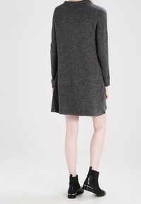 Vestito maglione grigio scuro lavorato a maglia con maniche lunghe, scollo rotondo e una vestibilità comoda, abbinato a stivaletti neri alla caviglia. Texture liscia.