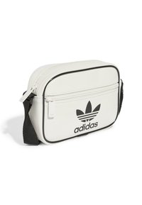 Borsa a tracolla bianca in pelle con accenti neri, dotata di chiusura superiore a zip e grande logo Adidas in nero con design a tre strisce.
