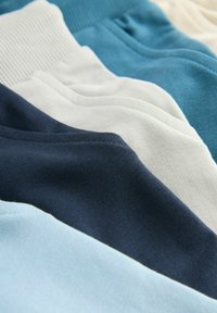 Katoenen stofsecties in tinten lichtblauw, donkerblauw en gebroken wit, met gladde texturen en geribbelde details langs de randen.
