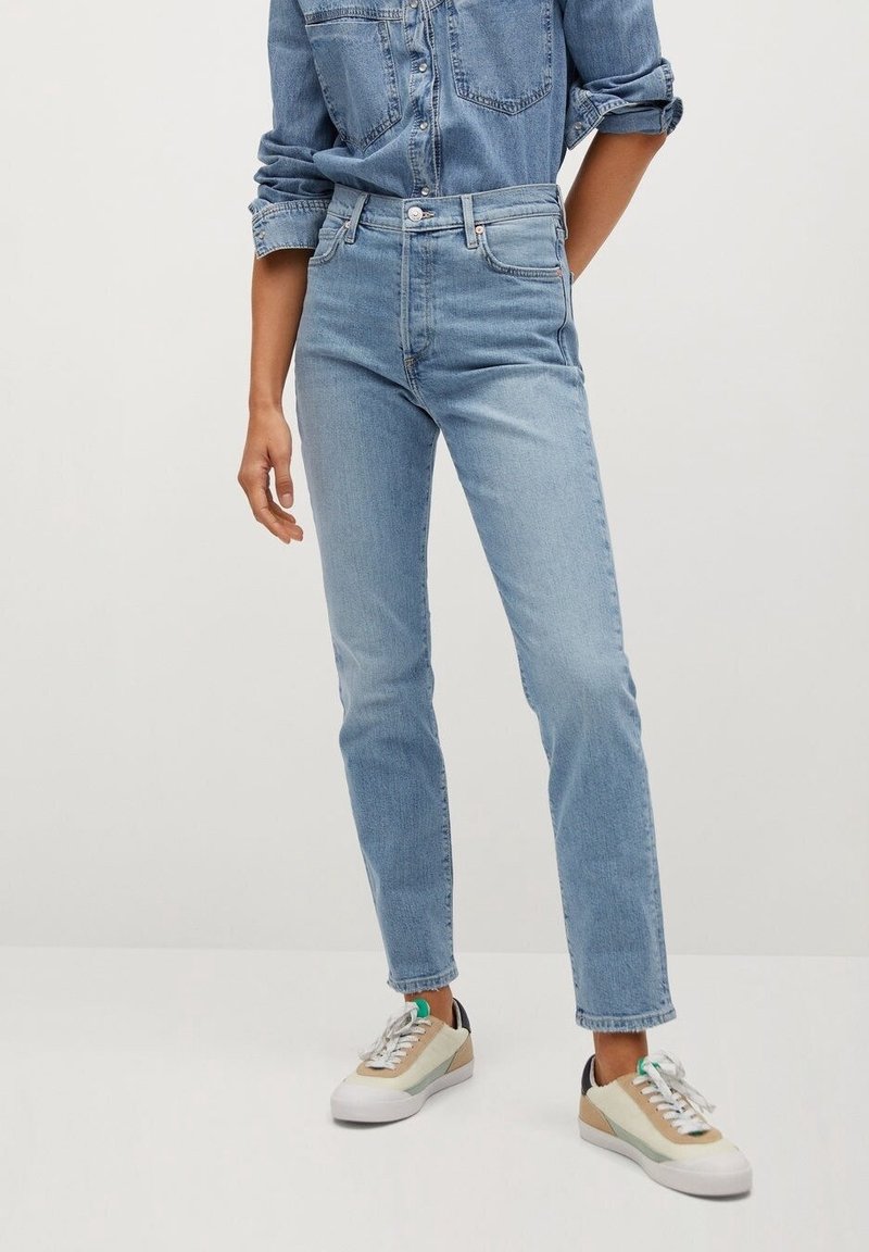 Jean bleu clair taille haute avec une coupe slim, en denim. Associé à des baskets multicolores avec une semelle et des lacets blancs.