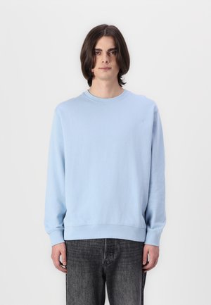 Lichtblauwe crewneck sweatshirt van zachte stof, met lange mouwen, geribde manchetten en een ontspannen pasvorm, gecombineerd met Donkergrijze jeans.