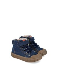 Zapatillas altas de denim azul marino con suelas de goma color marrón, que cuentan con ojales dorados, cordones azul oscuro y una correa de Velcro. Forradas con material color crema.