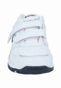 White athletic shoe featuring a synthetic upper, two adjustable Velcro straps, a padded collar, perforated design, and a black rubber sole.