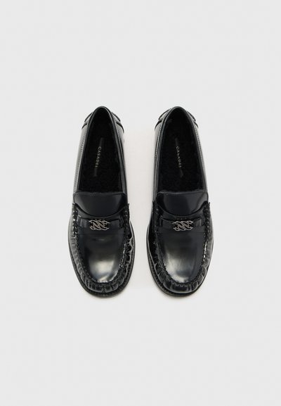 Schwarze Lacklederschuhe in mokassinarer Form mit einer gestickten Gestaltung, silbernen Akzenten und einem strukturierten schwarzen Innenfutter.