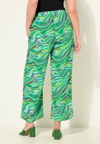 Groene wijde broek met een patroon van draaiende ontwerpen in verschillende tinten groen, paars en blauw, voorzien van een elastische tailleband en zakken.