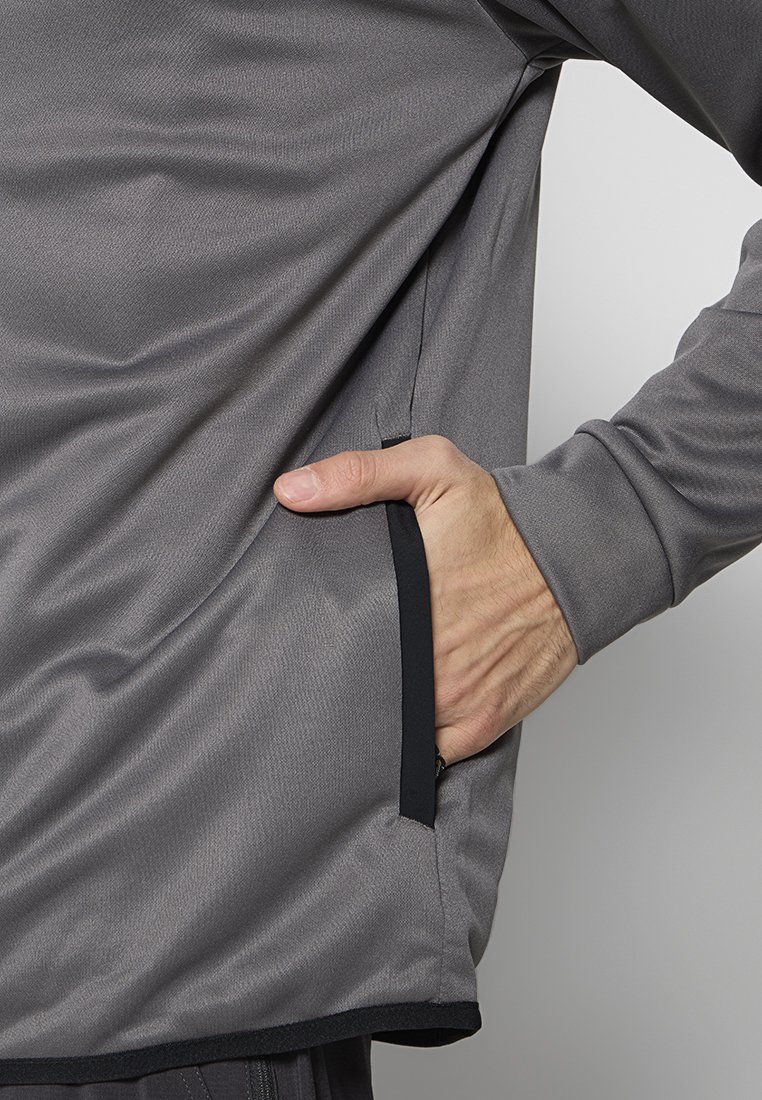 Graues Langarmshirt aus strukturiertem Stoff, mit seitlicher Tasche und kontrastierendem schwarzen Saum, das eine lässige Passform und ein entspanntes Design zeigt.