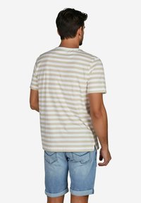 Beige-weißer gestreifter T-Shirt mit kurzen Ärmeln, lockere Passform, aus Baumwollmaterial, Rückansicht, kombiniert mit hellblauen, hochgekrempelten Jeansshorts.