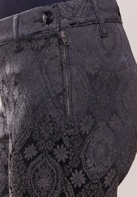 Mörkblå mönstrade byxor med en texturerad jacquarddesign, med dragkedja och en enkel knappstängning.