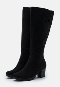 Bottes noires pour femmes montant jusqu'aux genoux avec talons carrés et coutures décoratives subtiles sur les côtés, présentées sur un fond blanc.