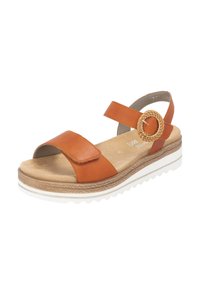 Sandale en cuir brun avec une sangle ajustable, un accent tissé circulaire et une semelle intérieure rembourrée sur une semelle compensée blanche et brune.