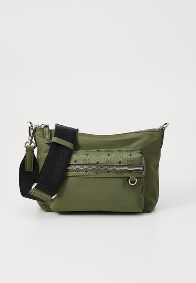 Sac en nylon vert avec une poche zippée à l'avant, motif texturé, bandoulière noire réglable et accents en métal argenté.