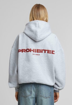 Gray hoodie with a large red "PROHIBITED" text and "10119, BERLIN" underneath. Features a spacious hood and loose fit.
