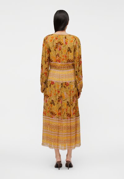 Μάξι φόρεμα σε κίτρινο ύφασμα με λουλουδάτα και πεταλούδες σχέδια. Μακριά μανίκια, εφαρμοστή μέση και ροδαλό φόρεμα με στρώσεις διακοσμητικών μοτίβων.