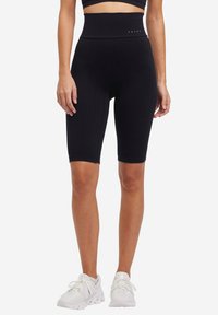 Pantaloni da ciclismo neri a maglia con vita alta, caratterizzati da un motivo testurizzato e un design aderente. Il nome del marchio "FALKE" è visibile sulla vita.