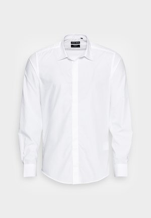 Camisa blanca de manga larga fabricada en una tela suave, con cuello abotonado y parte frontal recta con tapeta oculta.