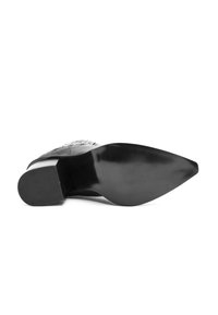 Zapato negro de tacón alto con punta afilada y parte superior de cuero suave. La suela es plana y ligeramente contorneada, con un acabado brillante.