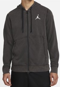 Felpa con zip grigia scura e finitura testurizzata, dotata di tasca a marsupio frontale e logo Jumpman bianco sul lato sinistro del petto.