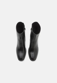 Black leather ankle boots with a smooth finish, square toe, and zipper detailing on the back. Interior lined with soft material.