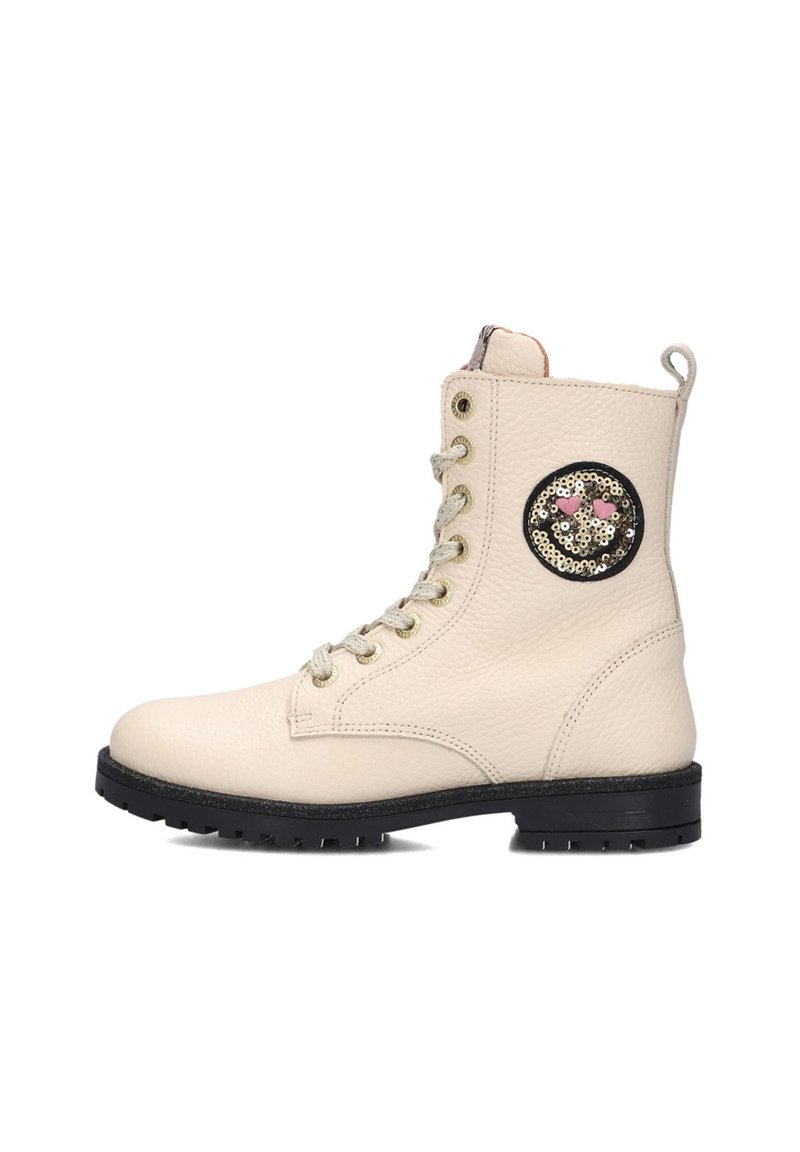 Crème leren enkellaars met een gestructureerd oppervlak, zwarte rubberen zool, gouden veterogen en een ronde, gepailleerde patch aan de buitenzijde.