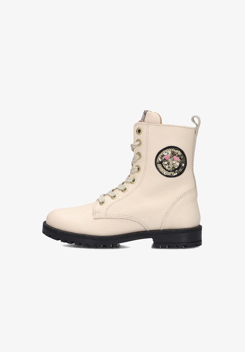 Cream leather ankle boot with textured surface, black rubber sole, gold eyelets, and a round sequined patch on the outer side.