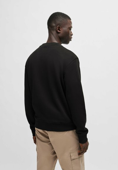 Sweatshirt noir avec un col rond, des poignets et un ourlet côtelés. Le tissu est lisse et doux, avec une coupe décontractée.