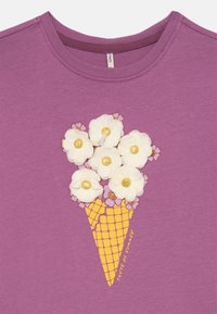 Lilla bomullsskjorte med et gult iskremkjegle-design, hvite blomstapplikasjoner og gyldne midtpunkter, merket "Smaken av sommer."