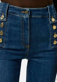 Jeans in denim a vita alta di colore blu scuro, con bottoni dorati e cuciture a contrasto sui lati e sulle tasche anteriori.