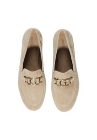 Mocasines de ante beige con un acento de logotipo en tono dorado en la parte frontal. Punta en forma de almendra y textura suave, diseñados para ser calzados fácilmente.
