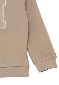 Felpa beige con logo "1" in tessuto pile. Polsini e orlo a coste. Piccola patch con logo nei colori rosso, bianco e blu sulla manica. Misto cotone morbido.