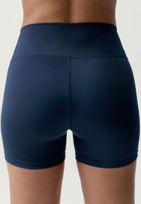 Shorts deportivos de cintura alta en azul marino, con una tela suave y elástica. Presentan un diseño sin costuras y una longitud ajustada a mitad del muslo.