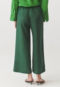 Groene wijde broek met een elastische tailleband, gemaakt van een soepele stof, met een nette zoom en een ontspannen pasvorm.