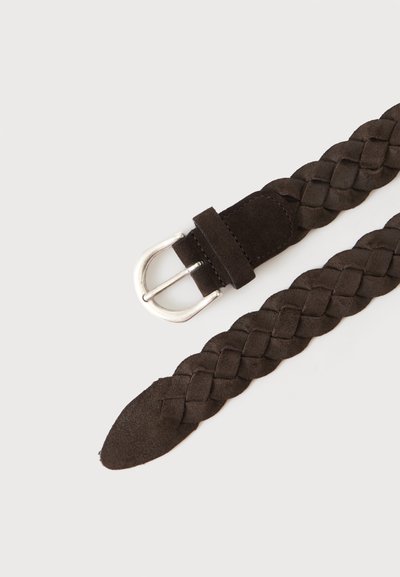 Ceinture en suède marron foncé tressée avec une boucle en métal argenté sur un fond clair.
