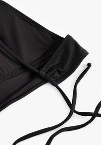 Top bikini nero realizzato in un tessuto liscio e elasticizzato. Presenta lacci regolabili, cuciture raffinate e una finitura con bordo curvo.
