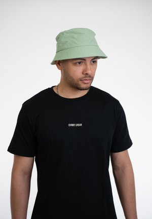 Grønne bøttehat med stikning og ventilationshuller, båret med en sort t-shirt med hvid tekst "JOHNNY URBAN." Enkelt, afslappet design.