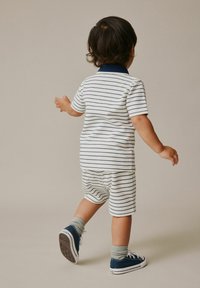 Stribet polo i kortærmet og shorts sæt i hvid med marineblå striber, kombineret med marineblå sneakers og grå sokker. Blødt stof, afslappet pasform.