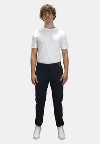 Witte T-shirt met korte mouwen in combinatie met marineblauwe broek met koord en witte sneakers. De stof lijkt glad, zonder zichtbare patronen of accenten.