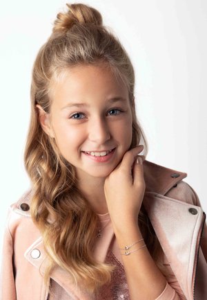 Veste en suédine rose avec quincaillerie argentée, haut rose clair avec des accents en sequins, présentant un bracelet argenté avec des détails en forme de cœur.