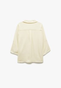 Cremefarbene Bluse mit Kragen, Dreiviertelärmeln und einer Naht hinten. Aus strukturiertem Stoff gefertigt, mit lockerem Schnitt.
