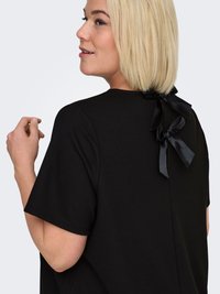 Black short-sleeve top with textured fabric, featuring a round neckline and two black satin bows at the back. Relaxed fit, simple design.