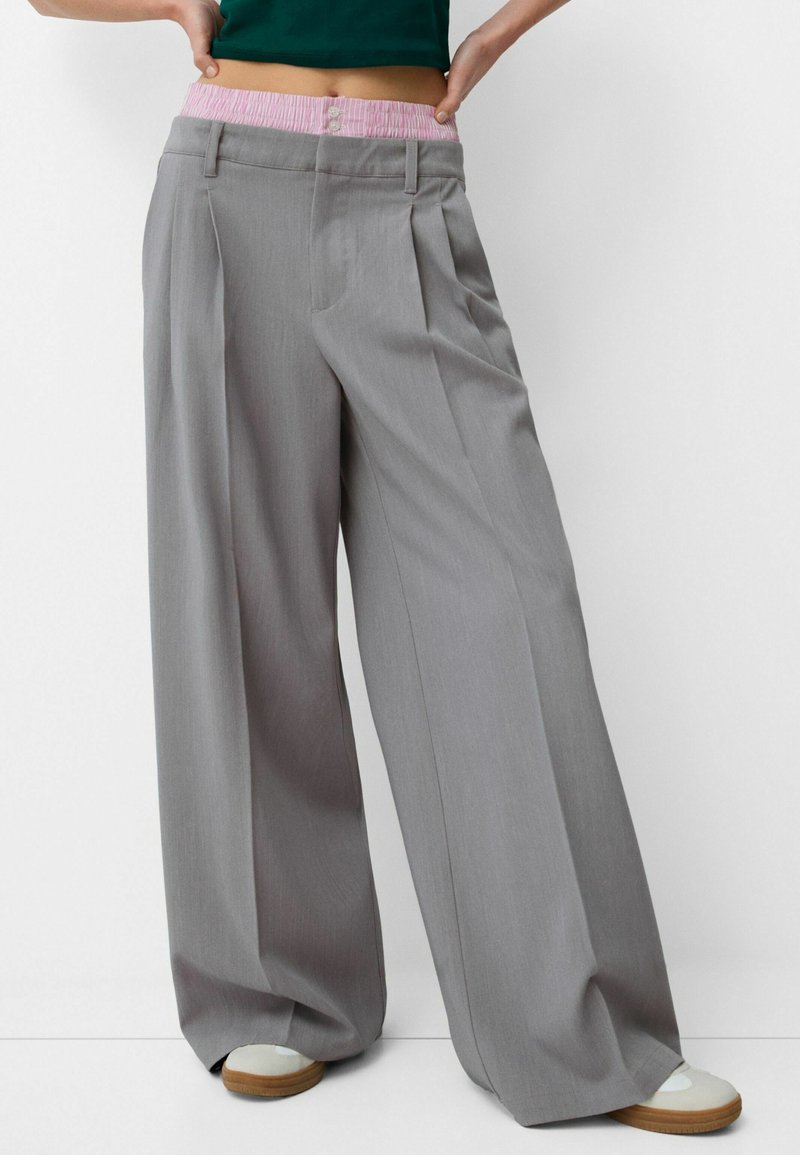 Grijze wijde broek met een roze gestreepte elastische tailleband, voorzien van voorplooien en een soepele stoftructuur.