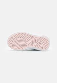 Semelle de basket blanche avec un motif en caoutchouc rose. Présente une surface texturée et une étiquette de logo portant la mention "LACOSTE". Forme incurvée et arrondie.