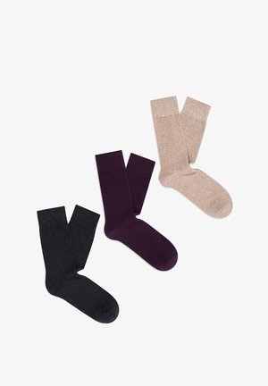 Trzy pary skarpet: jedna czarna, jedna ciemnofioletowa, jedna jasnobeżowa. Gładka tekstura, prążkowane ściągacze i długość do połowy łydki.