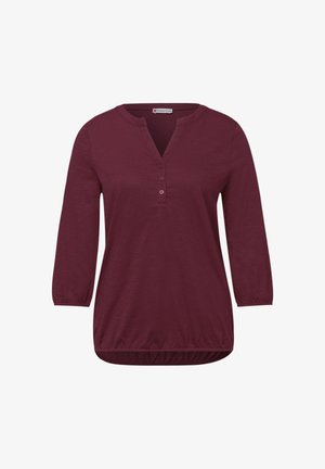 Bluzka o długim rękawie w kolorze śliwkowym, z trzema guzikami, okrągłym dekoltem z wycięciem oraz elastycznymi mankietami i dołem.