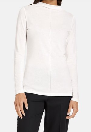 Long-sleeve, fitted top in soft white fabric with a high neck, featuring a center seam down the back and structured shoulder design.