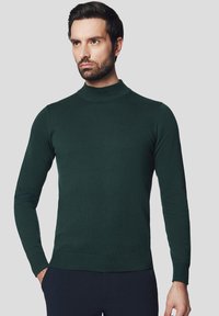 Ciemnozielony sweter typu golf wyk wykonany z dzianiny, z długimi rękawami i dopasowanym krojem, z prążkowanym wykończeniem u dołu i pod szyją.