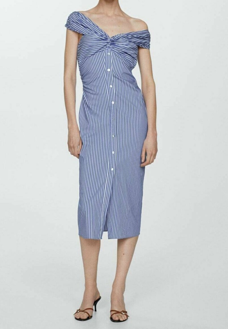Femme portant une robe midi rayée bleu et blanc, épaules dénudées, avec des boutons sur le devant, associée à des escarpins marron à bouts ouverts.