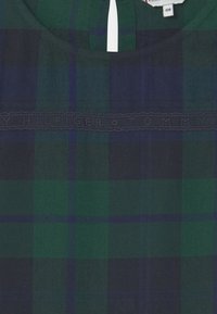 Zelená a námořnická kostkovaná košile s kulatým výstřihem a vyšitým logem "Tommy Hilfiger" na hrudi. Měkká bavlněná tkanina.